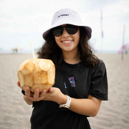 Samantha is holding a coconut with a straw and smiles